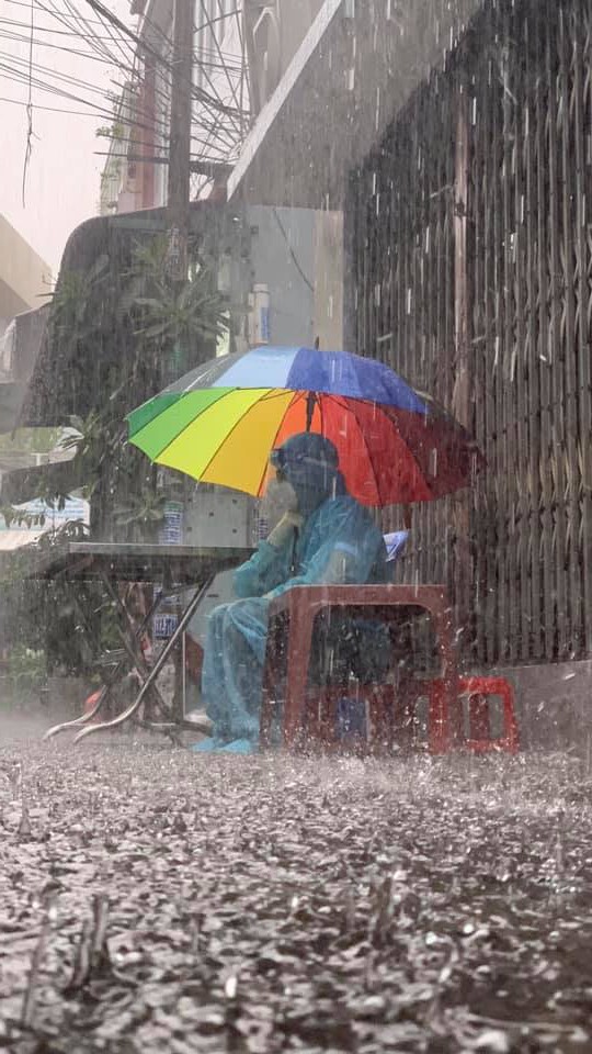 Chàng tình nguyện viên sẵn sàng cầm dù ngồi dưới mưa, nhường chỗ trú cho mọi người