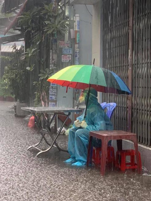 Chàng tình nguyện viên sẵn sàng cầm dù ngồi dưới mưa, nhường chỗ trú cho mọi người